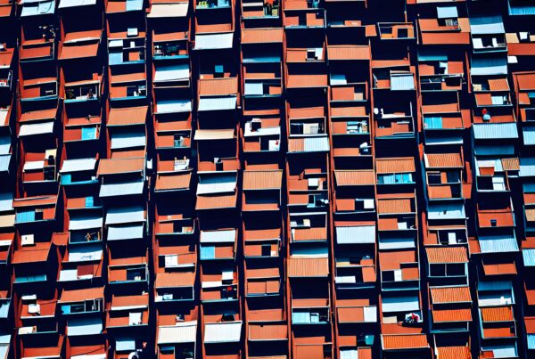 Image of modern residential building facade with red and grey balconies creating a geometric pattern.