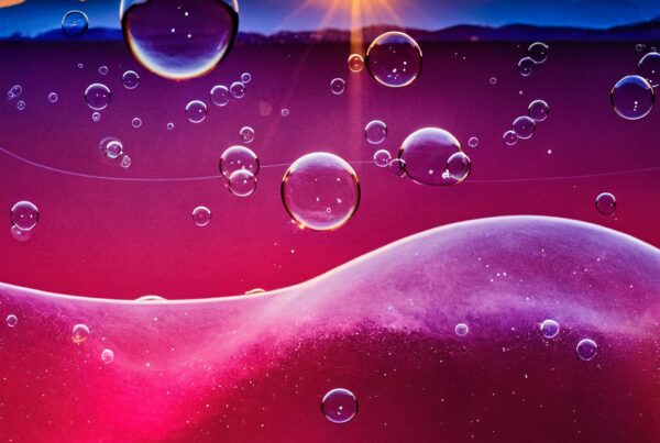 Vibrant sunset with surreal bubbles floating above colorful landscape in dreamy atmosphere.