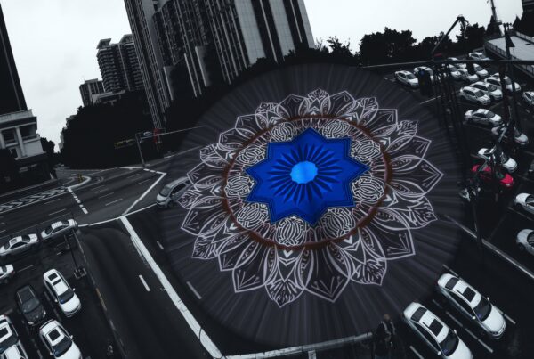 A vibrant blue mandala overlays a busy urban intersection, blending intricate art with bustling city life.