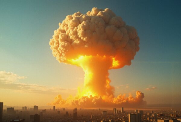 A bright mushroom cloud rises over a city at sunset, casting an orange glow against a clear blue sky.