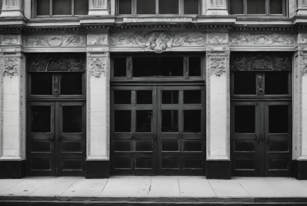 Black and white photo of an ornate historical building facade with detailed carvings and large wooden doors.