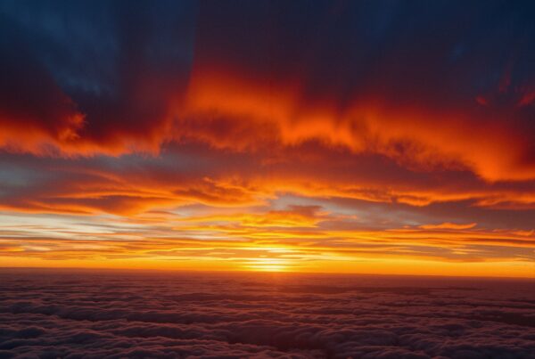 A stunning sunset with vibrant orange and red hues over a cloud-filled horizon, creating a dramatic and peaceful landscape.