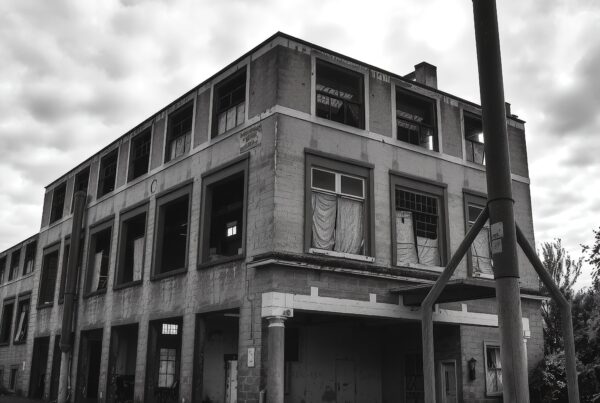 Abandoned industrial building under cloudy sky.