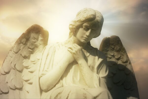 A serene angel statue with wings, bathed in golden light against a peaceful time-lapse sky backdrop.