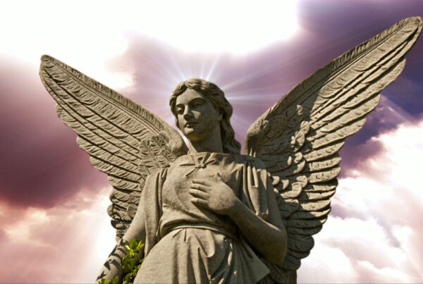 4K video loop of a stone angel statue with radiant wings and a halo effect against a dramatic purple and white time-lapse sky.