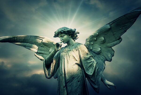 A serene angel statue with outstretched wings and a peaceful expression, set against a dramatic cloudy sky with rays of light, symbolizing ethereal silence and contemplation.