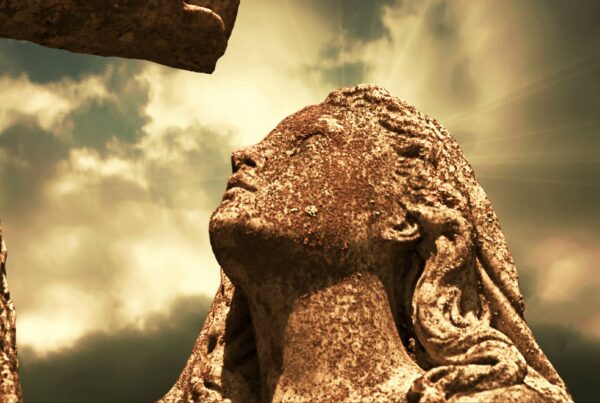 4K video loop of a weathered stone statue looking skyward with dramatic time-lapse clouds and sun rays.
