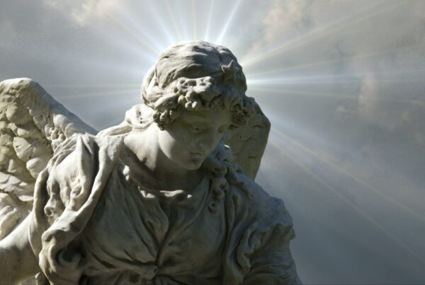 4K video loop of a stone angel statue with a radiant halo against a time-lapse cloudy sky.