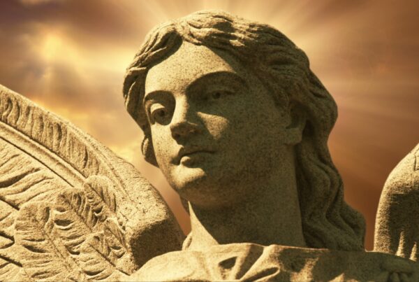 4K looping video of a stone angel statue with radiant halo effects in a golden time-lapse sky.