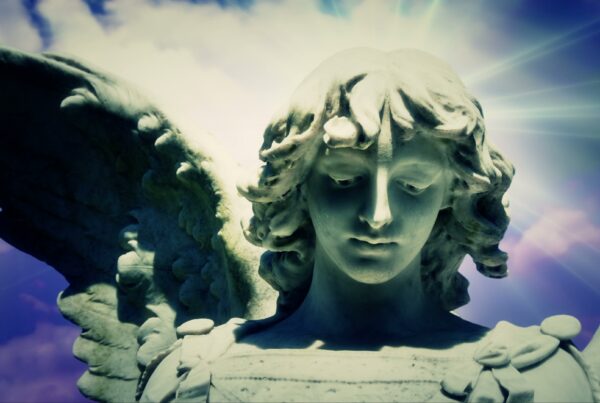 4K video loop of an Angel statue with open wings against a heavenly time-lapse sky, illuminated by ethereal light.