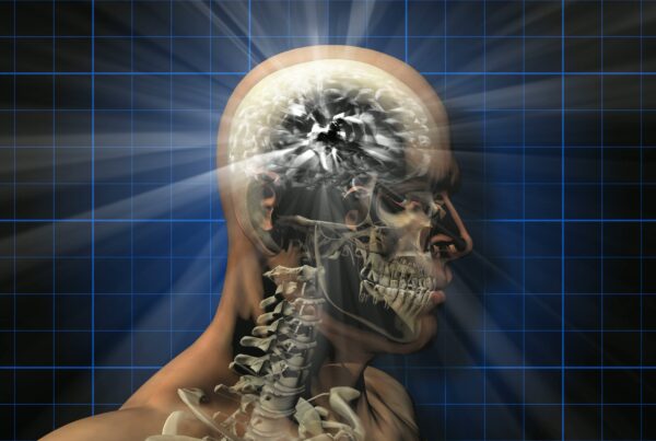 X-ray video loop of a rotating human skull with radiant brain activity, set against a blue grid background.