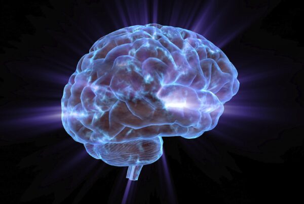 4K video loop of a glowing digital rendering of a brain with blue and purple hues against a dark background, radiating light beams outward.