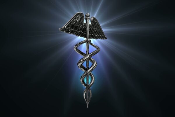 Looping video of a rotating, metallic caduceus symbol with two entwined serpents and wings, set against a radiant dark background.