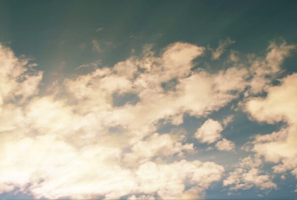 A 4K video loop of a picturesque time-lapse sky with fluffy golden clouds against a blue backdrop, illuminated by soft sunlight.