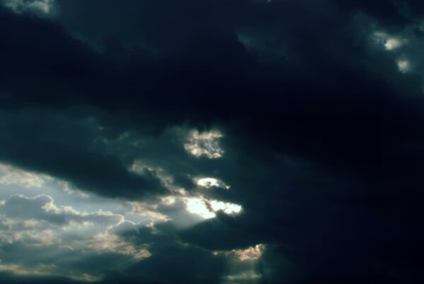 Dramatic stormy sky with sunlight peeking through dark time-lapse clouds.