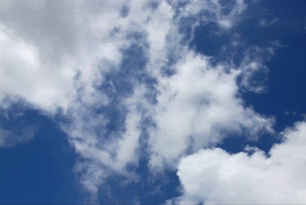 A bright 4K video of a blue sky with fluffy white time-lapse clouds floating peacefully.