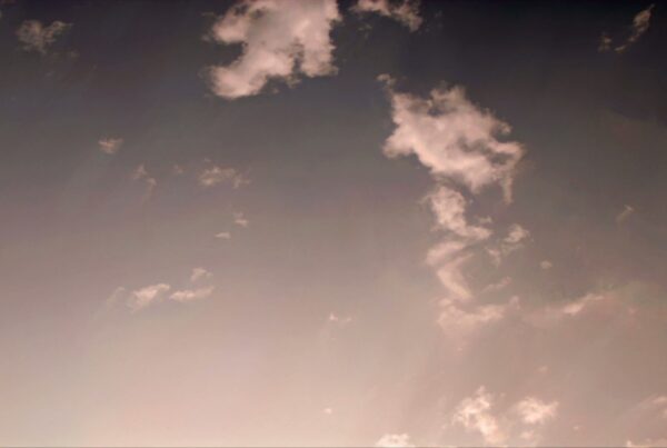 A tranquil time-lapse sky during sunrise or sunset with wispy clouds and a pink-purple gradient, evoking a peaceful and serene atmosphere.