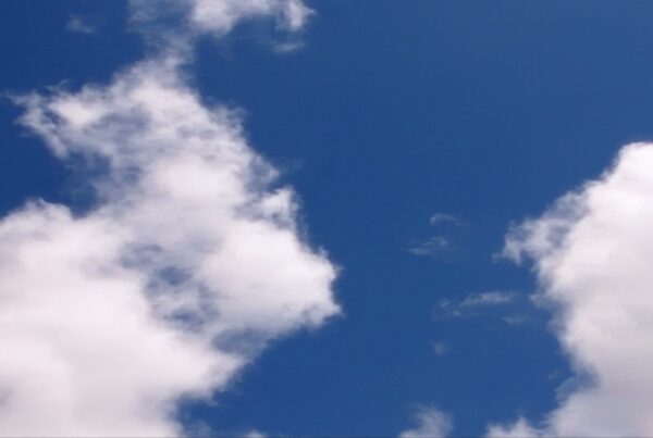 A vibrant blue sky filled with fluffy white time-lapse clouds, creating a serene and peaceful atmosphere as sunlight highlights their soft texture.