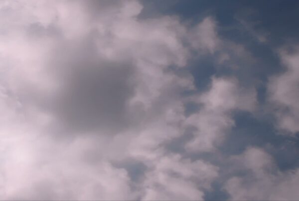 A tranquil view of a clear blue sky with scattered fluffy time-lapse clouds, showcasing a serene and peaceful atmosphere.