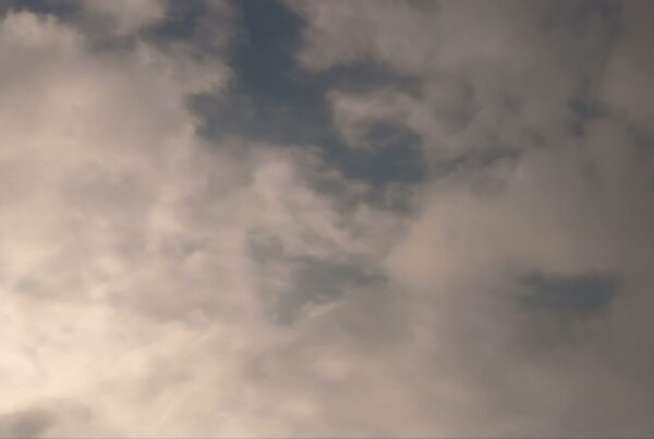 Soft, time-lapse clouds drifting across a blue sky, showcasing a tranquil and serene atmosphere in a natural landscape.