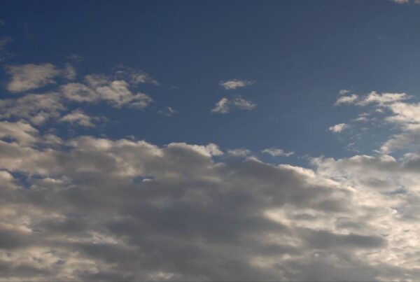 A tranquil sky with a gradient of blue and scattered wispy time-lapse clouds, creating a serene and peaceful atmosphere.
