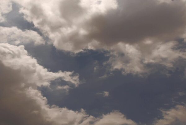 Time-lapse storm clouds gather in a dramatic sky with a small patch of blue visible, creating a striking contrast and highlighting the atmospheric tension.