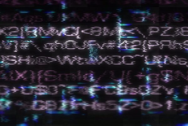 Abstract video loop of distorted digital text with colorful glitches, featuring purple, blue, and green hues against a dark background, reminiscent of an old CRT monitor screen.