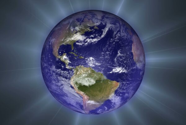 Video loop of a rotating Earth taken from space, with realistic cloud formations and vibrant colors, against a dark background with radiant light beams.