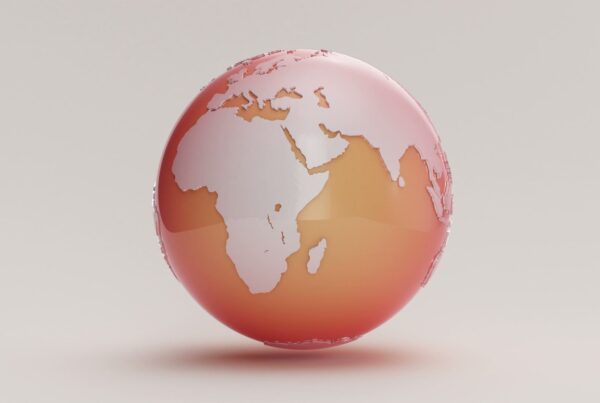 A 3D globe animation loop with continents in a gradient from red to orange on a plain background.