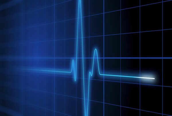 Looping 4K video of a digital heartbeat monitor with glowing blue pulse line on grid background.