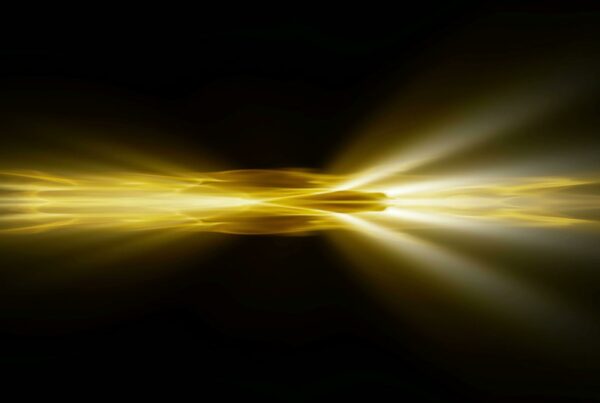 Abstract video loop of vibrant golden light beams radiating from a central point against a dark background, creating a striking and dynamic energy burst effect.