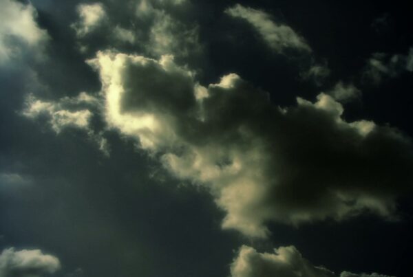 The video displays a dramatic sky filled with dark, billowing time-lapse clouds against a dimly lit background.