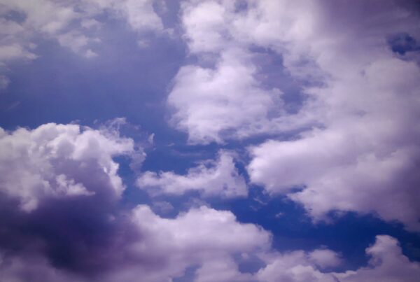 A vibrant sky filled with fluffy, white time-lapse clouds against a deep blue background.
