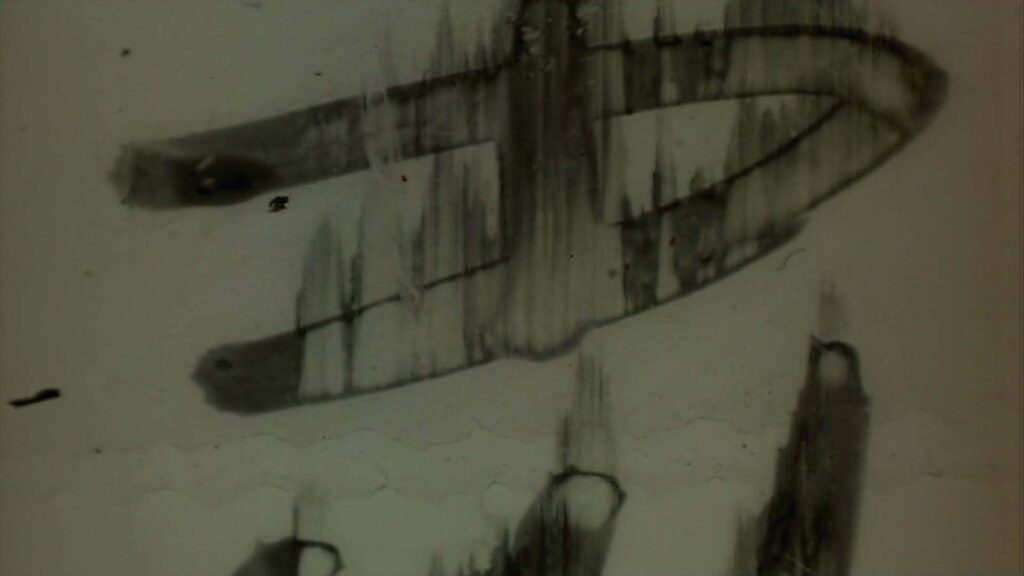 Looping video of aged, damaged film leader with dust, scratches and writing.