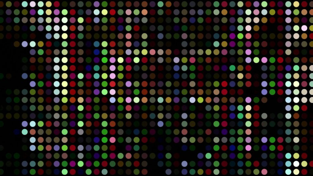 Vibrant multicolored dot matrix video loop on a black background, featuring a grid of uniform circles in random animating colors such as red, blue, and green, creating a pixelated and abstract digital art effect.