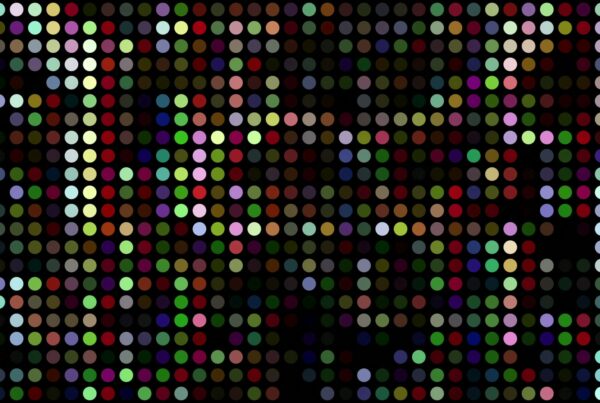 Vibrant multicolored dot matrix video loop on a black background, featuring a grid of uniform circles in random animating colors such as red, blue, and green, creating a pixelated and abstract digital art effect.