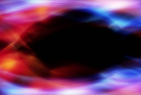 Abstract video loop of colorful swirling patterns with dominant red, purple, and blue hues surrounding a central dark void, creating a vibrant and fluid appearance.