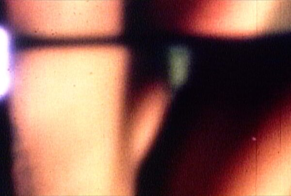 This 4K video loop shows a 16mm film being projected with abstract warm tones, film grain, and projector flare, evoking analog nostalgia and vintage cinematic textures.