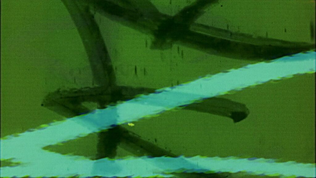 Looping video of vintage 16mm film leader with scratches, dust, hand-drawn markings, and cyan light streaks on a green background.