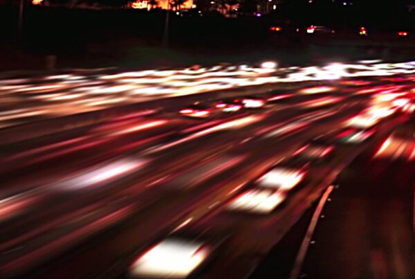 4K video loop of a nighttime highway with blurred light trails from moving traffic, showcasing headlight and taillight patterns in dynamic, vibrant lines.