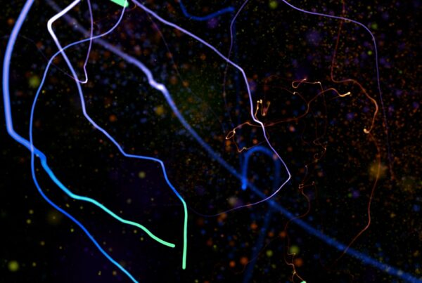 A vivid abstract 4K video loop featuring colorful, intertwining light trails and particles on a dark background.