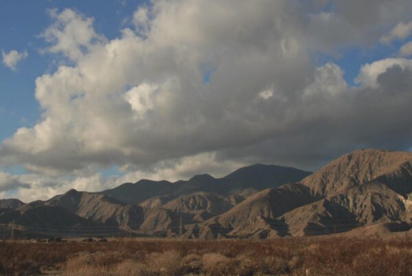 A stunning 4k video view of mountains under a time-lapse cloudy sky, with dry terrain below.