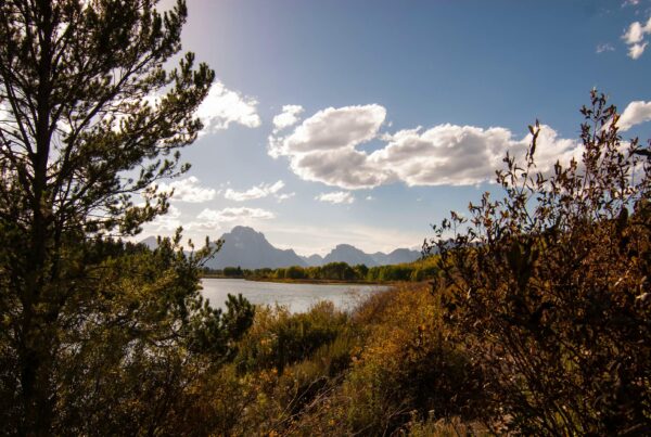 Serene 4K time-lapse landscape with mountains, lake, and autumn foliage.