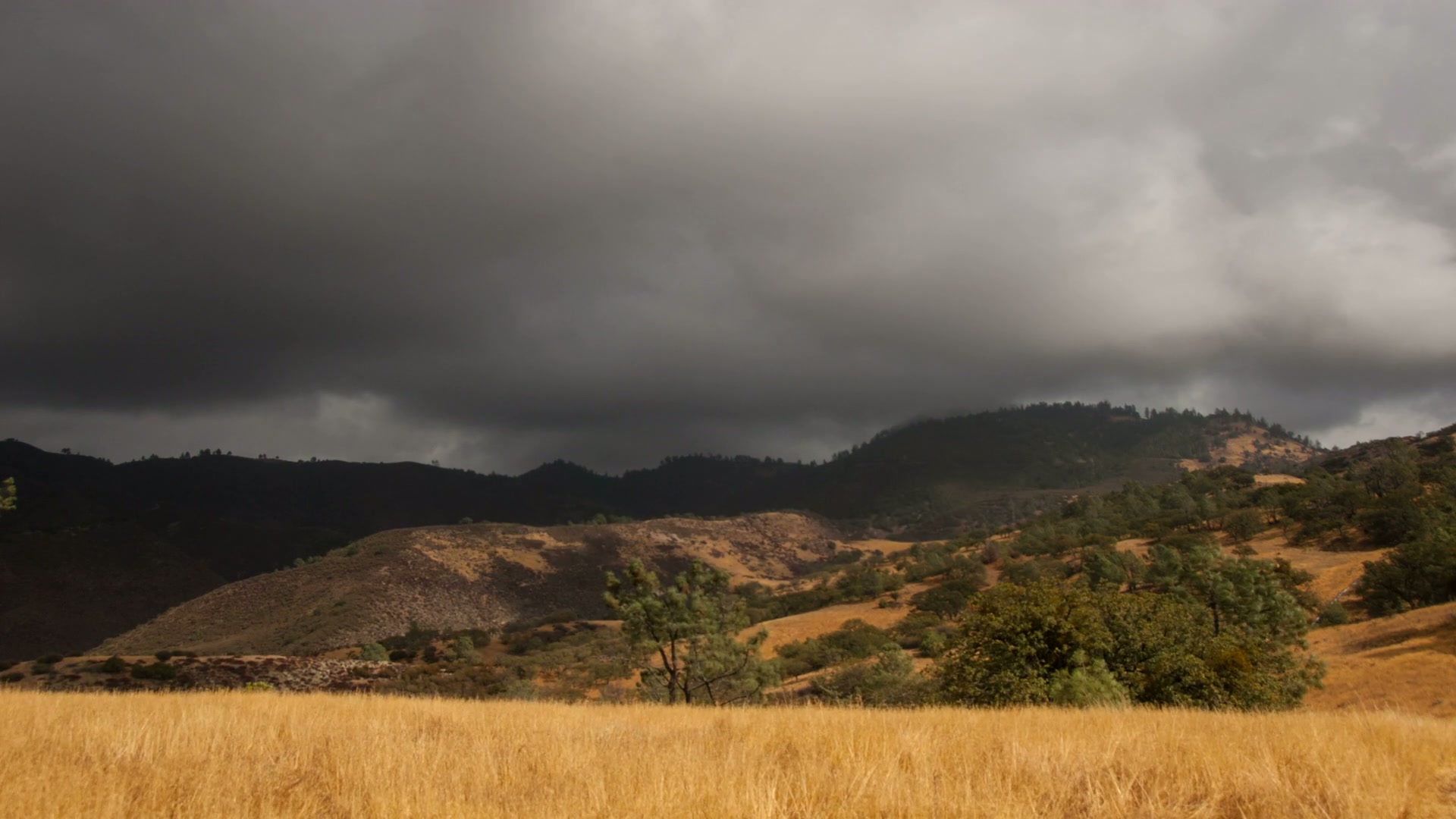 Approaching time-lapse storm over grassy hills