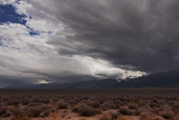 Dramatic desert landscape with time-lapse storm clouds over mountains.