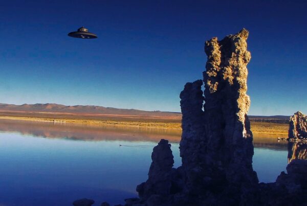 UFO hovering over reflective lake with tufa spires reflecting in calm waters under twilight sky.