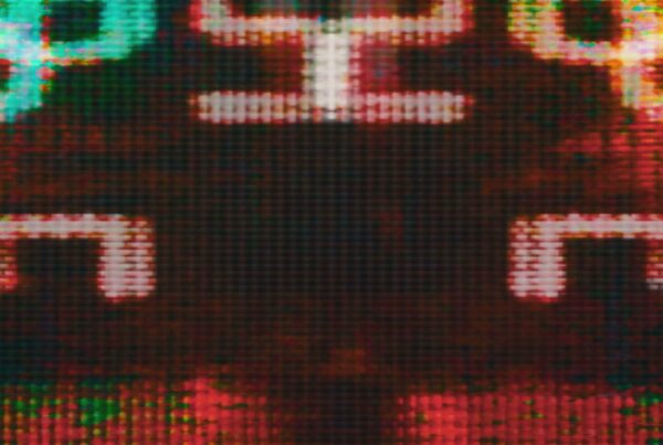 Close-up video loop of a digital screen displaying vibrant pixelated graphics in red, green, and yellow with an abstract pattern, highlighting the retro and technological aesthetic.
