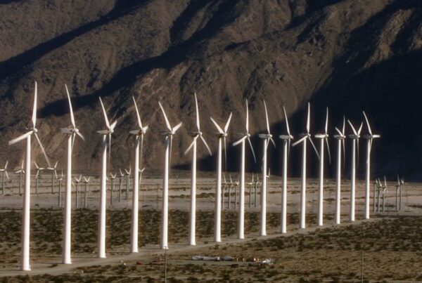 The video depicts a large wind farm set against the backdrop of a rugged, mountainous landscape.
