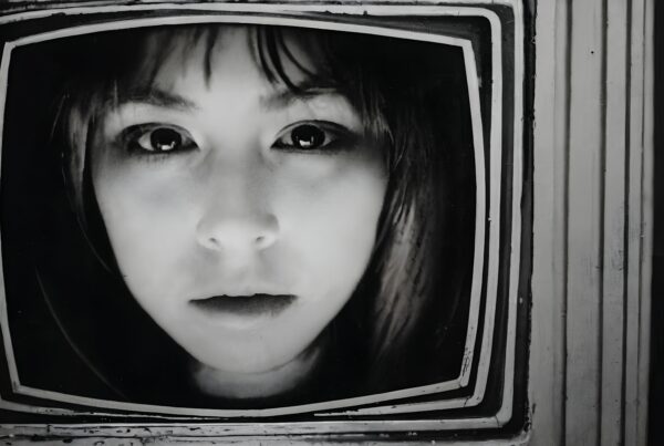 Black and white close-up of a woman's face in a vintage television screen, creating a nostalgic and intriguing scene.