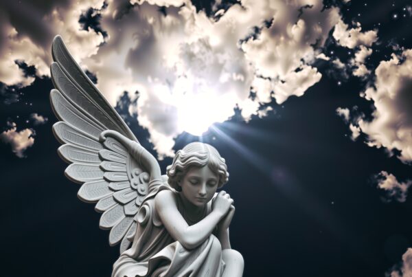 An angel statue with detailed wings against a dramatic sky with radiant clouds and sun.